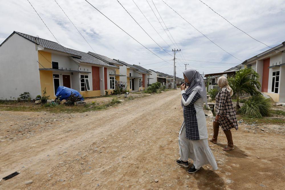 Warga melintas di depan rumah komplek KPR bersubsidi di Desa Lam Ujong Kecamatan Baitussalam, Aceh Besar, Aceh, Senin (3/8/2020). ANTARA FOTO/Irwansyah Putra