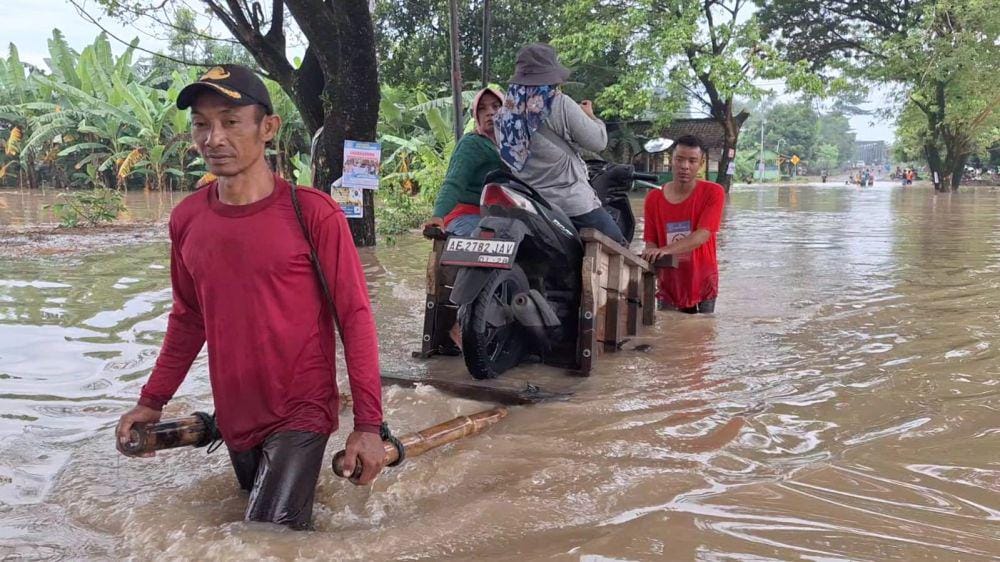 Warga desa Pangkur Ngawi terdampak banjir luapan Bengawan Madiun memindahkan kendaraanya dengan gerobak. IDN Times/ Riyanto