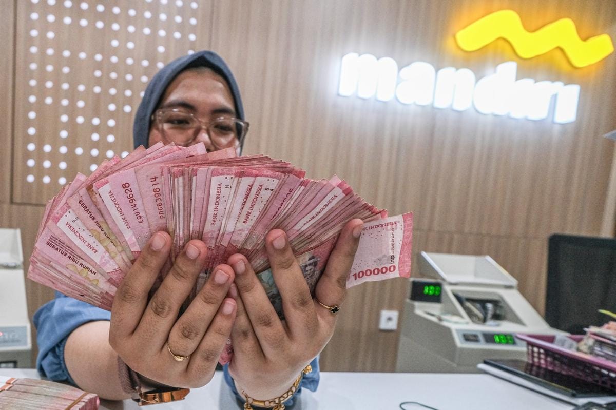 Ilustrasi karyawan menunjukkan uang di Bank Mandiri. (ANTARA FOTO/Andry Denisah)